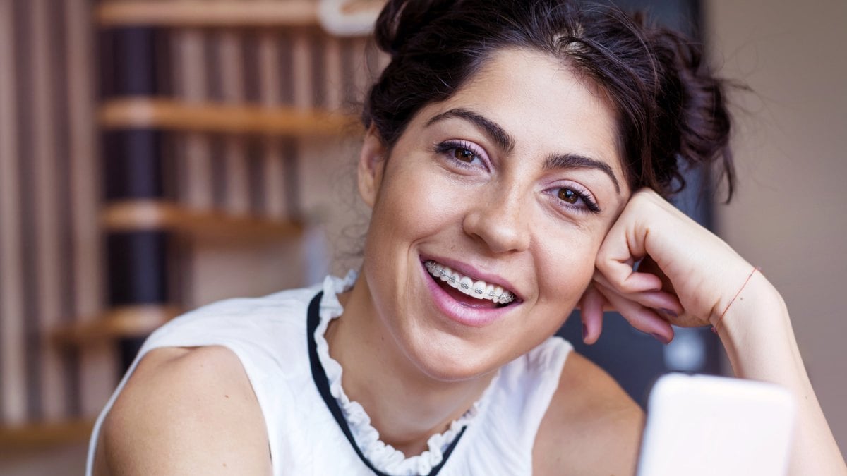 Adult patient smiling with LightForce custom braces at Garlock Orthodontics in Aurora, CO